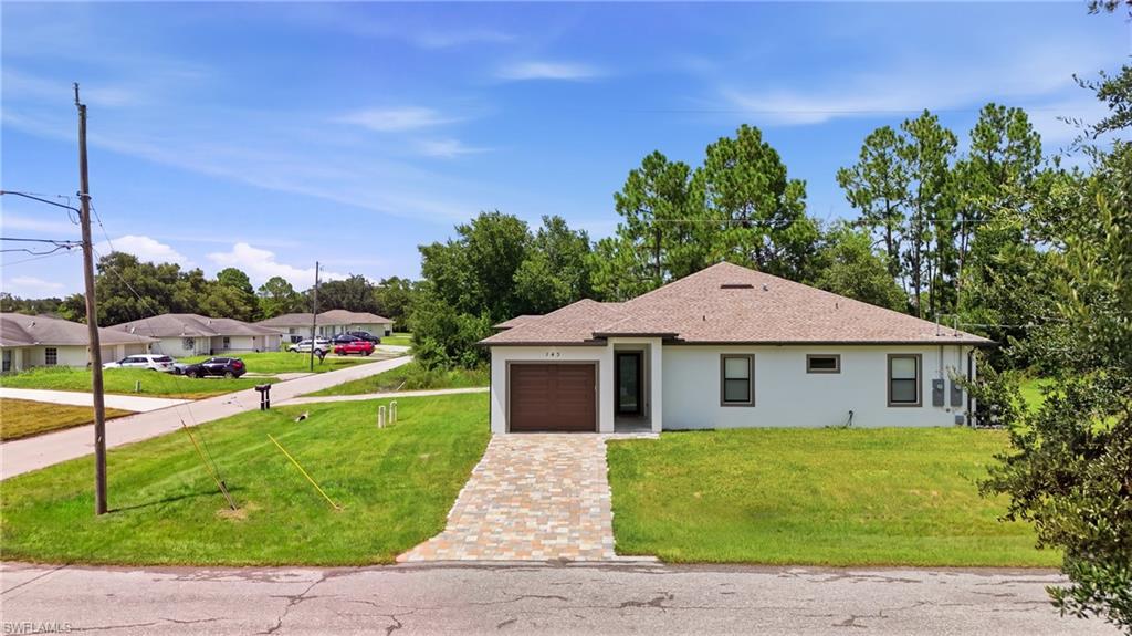 Single-story residence featuring a paver driveway, an integrated garage with a wood-finish door, and a brown shingle roof