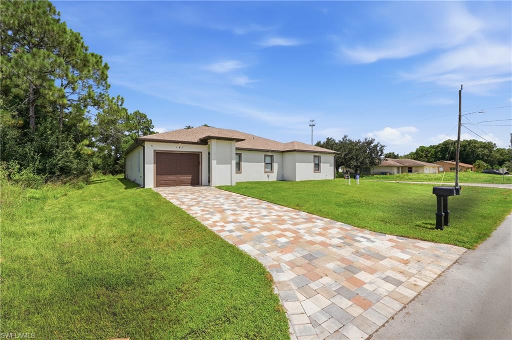 Exterior featuring a single-story design, a paver driveway, an attached garage with a brown door, and a light-colored stucco facade