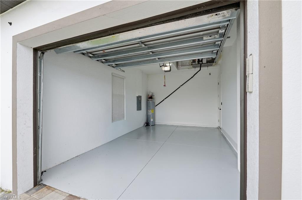 Spacious garage with light grey epoxy flooring, interior white walls, built-in window with horizontal blinds, and overhead lighting