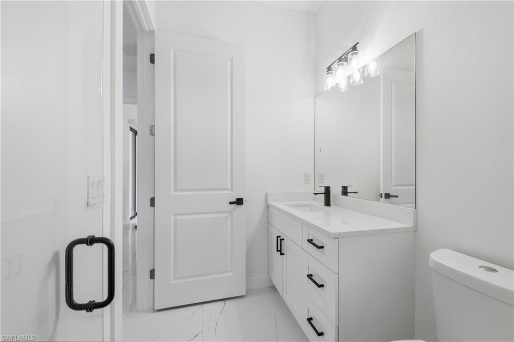 White vanity with quartz countertop, undermount sink, matte black faucet, and modern lighting fixture