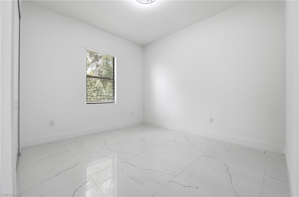 White walls with a window featuring horizontal blinds, and a ceiling-mounted light fixture above a tiled floor