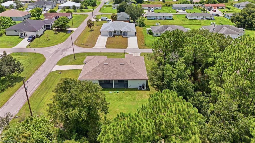 Expansive residential property with a brown shingle roof, light-colored exterior, and an uncovered concrete patio
