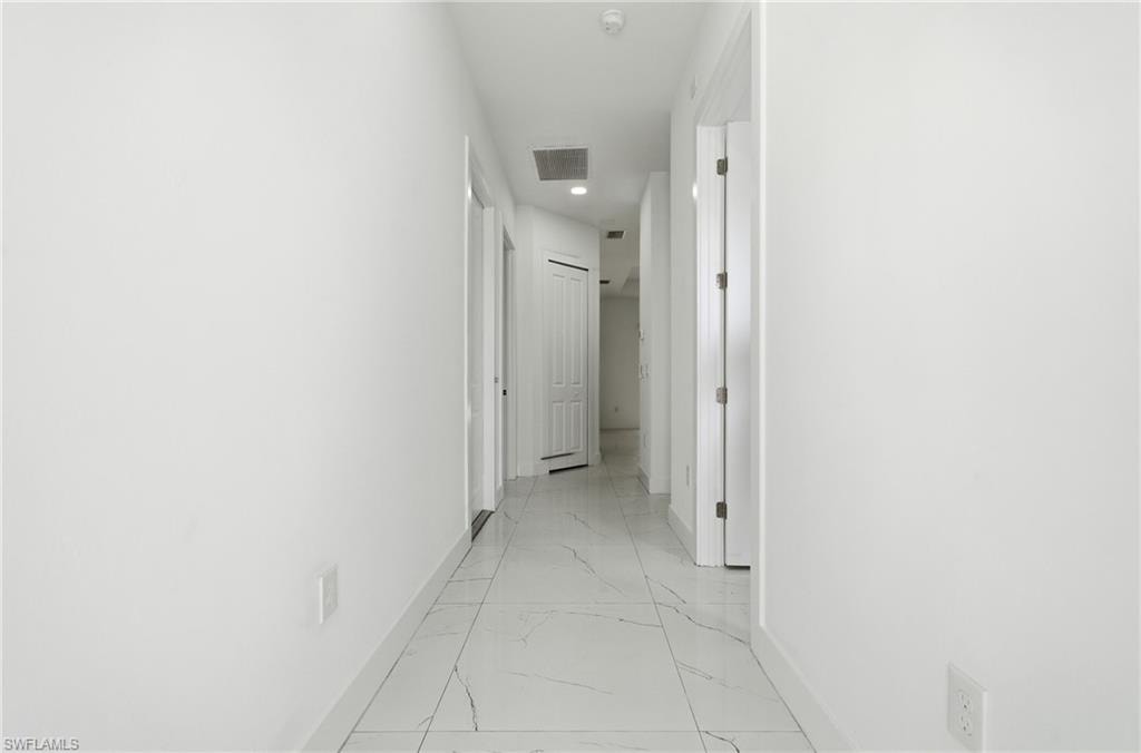 Hallway with light-toned walls and patterned tile flooring