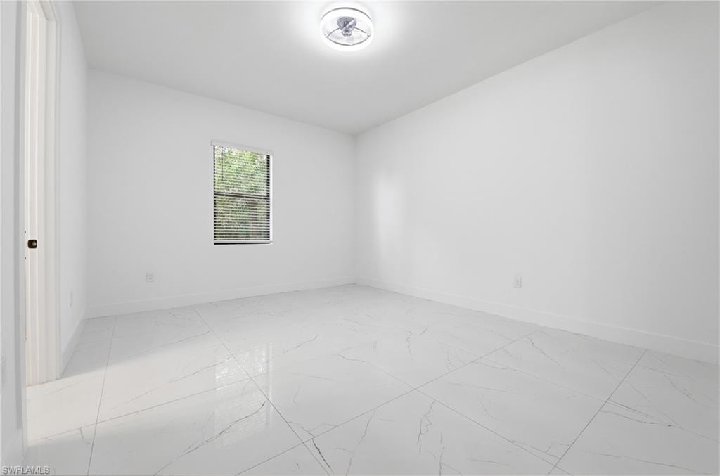 Recessed window with blinds, overhead flush-mount lighting, and large format tile flooring