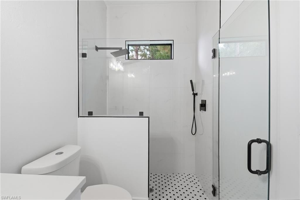 Glass-enclosed shower with matte black fixtures, rain shower head, and an accent window