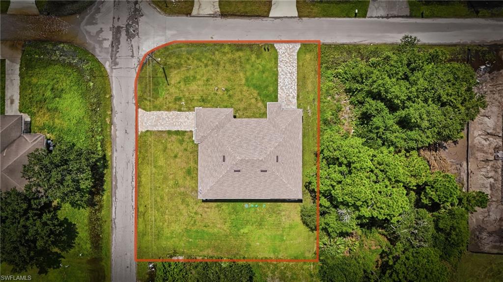 Aerial perspective showcasing the property's perimeter, a paved driveway, and established trees