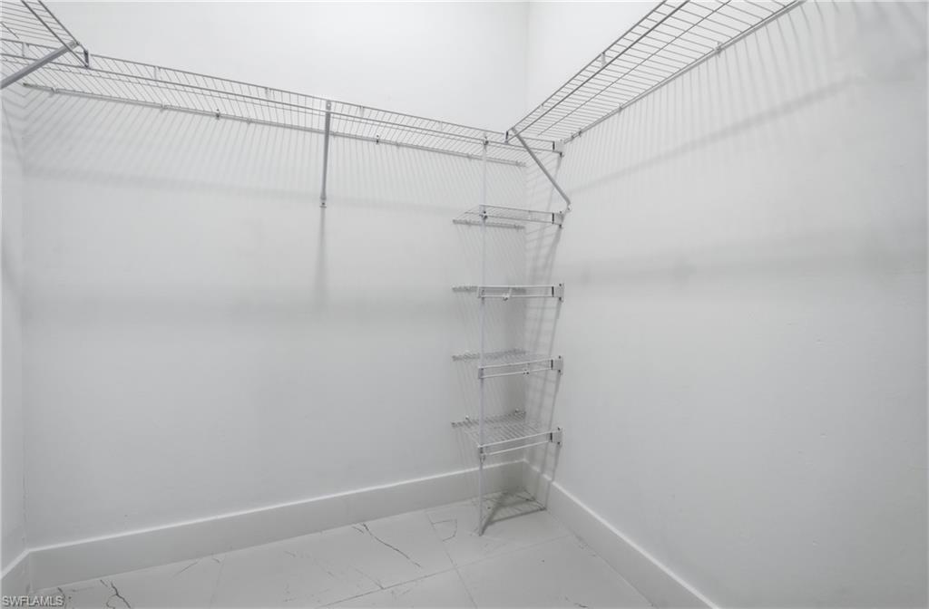 Built-in shelving and hanging rods with a white finish, complemented by large format tile flooring