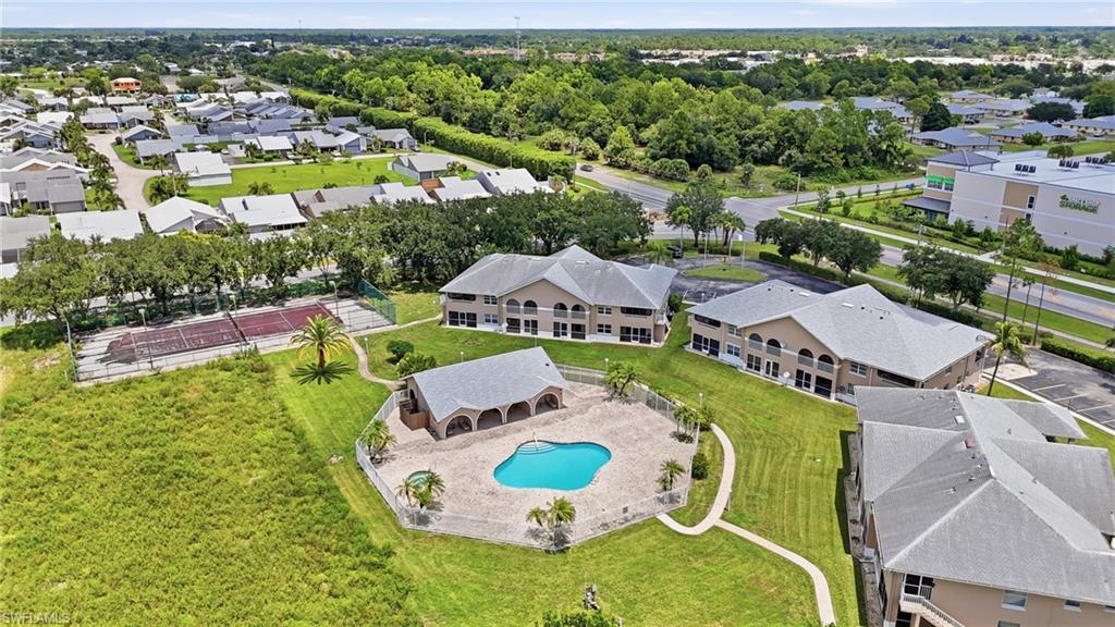 Expansive lawn surrounding a swimming pool with a covered pavilion and tennis courts