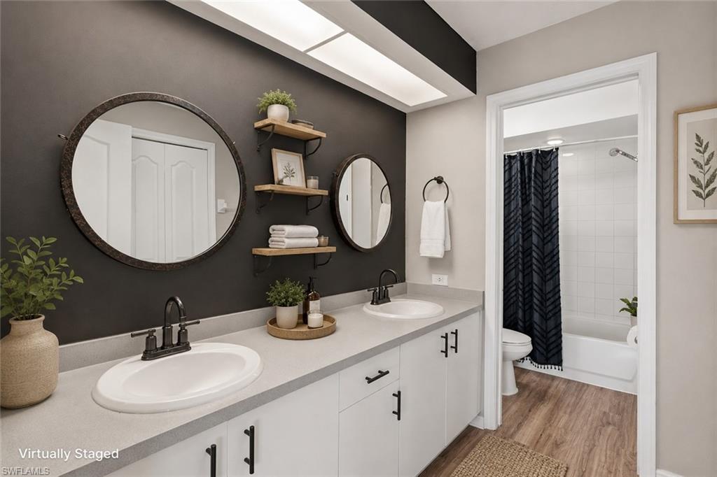 Dual vanity with undermount sinks, round framed mirrors, and wood-finish flooring