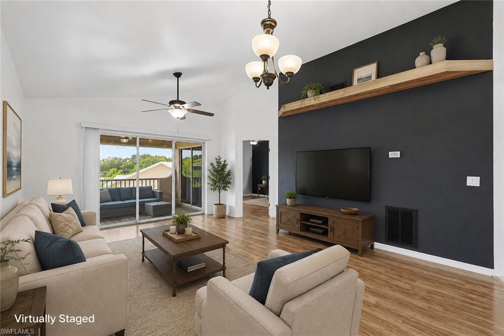 Vaulted ceilings with a ceiling fan, wood-finish flooring, and a sliding glass door leading to a balcony