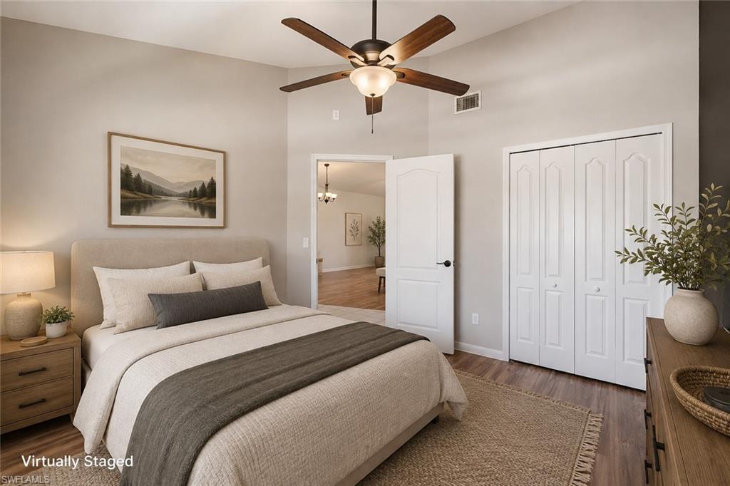 Vaulted ceiling with a ceiling fan, wood-finish flooring, and white bifold closet doors