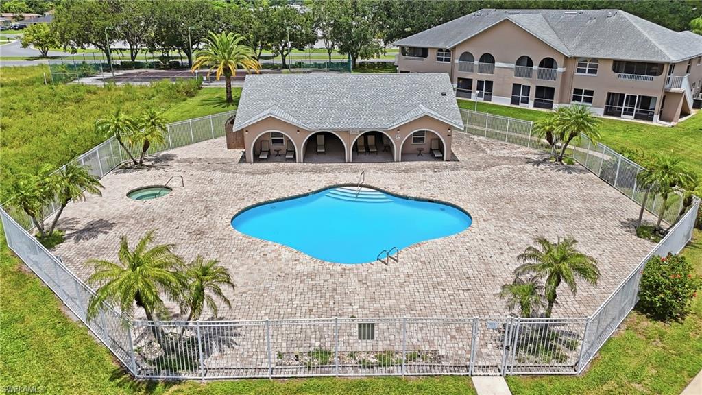 Pool area featuring a freeform swimming pool, integrated spa, paver deck, and surrounding fencing