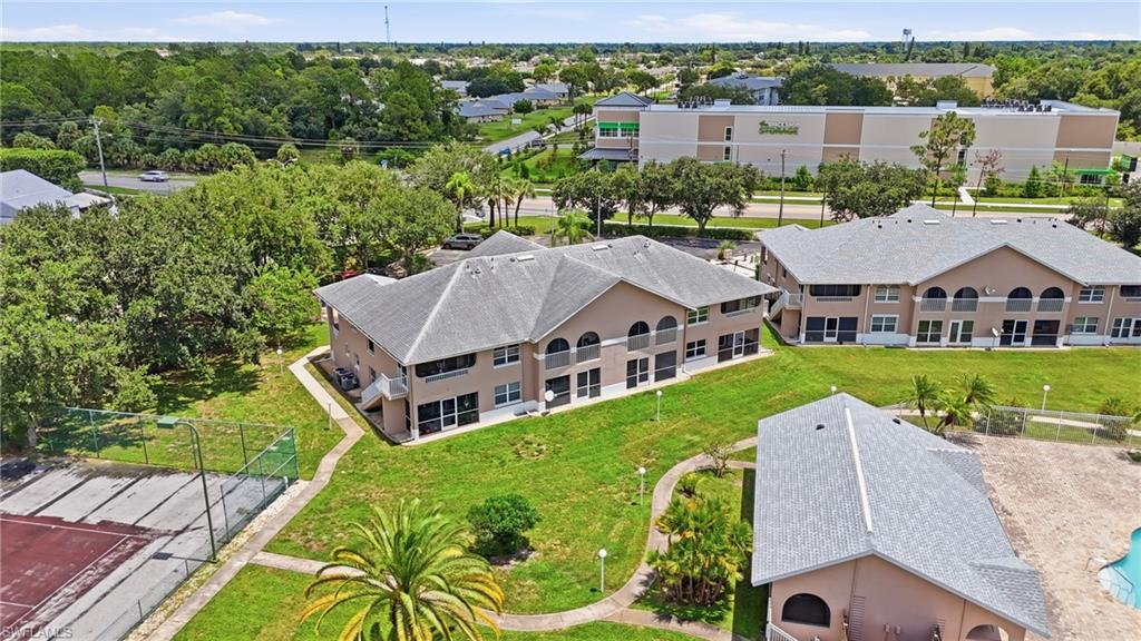 Multi-story residential buildings with individual balconies, surrounded by landscaped grounds and mature trees
