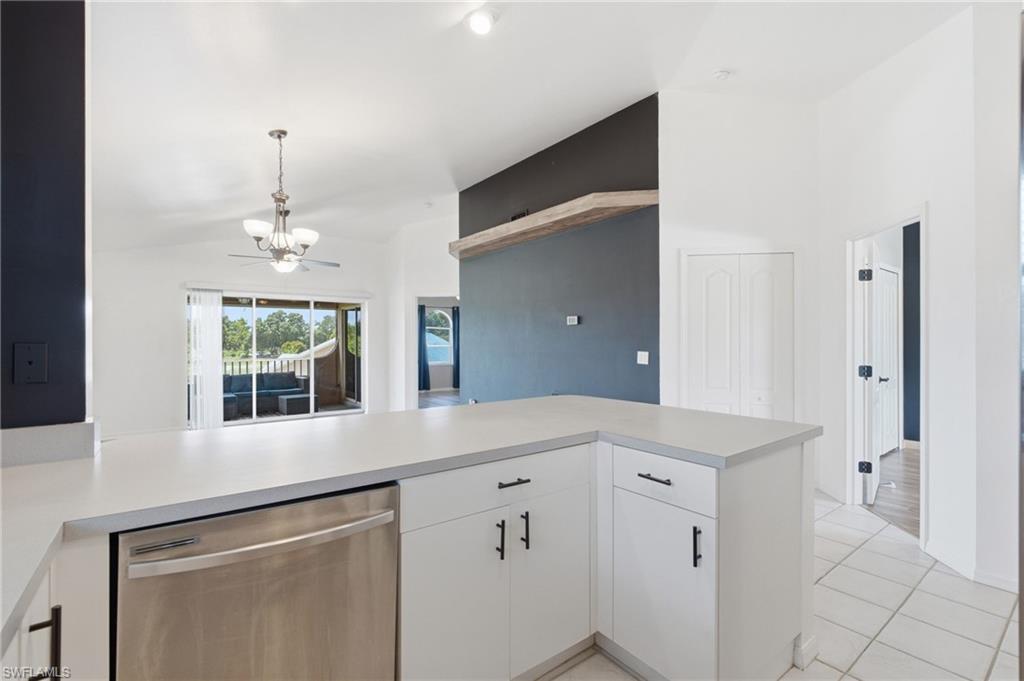 Open-concept kitchen featuring white cabinetry, light countertops, and a stainless steel dishwasher