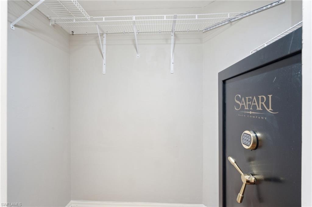 White wire shelving system with wall-mounted brackets and a large safe with a safe with combination lock and brass handle