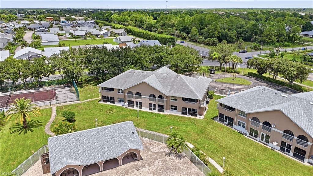 Expansive property featuring multiple residential structures with sloped roofs, a paved tennis court, and a covered outdoor recreation area