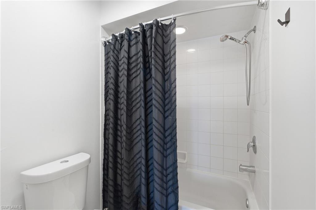Recessed lighting, tile shower surround, bathtub, and chrome fixtures