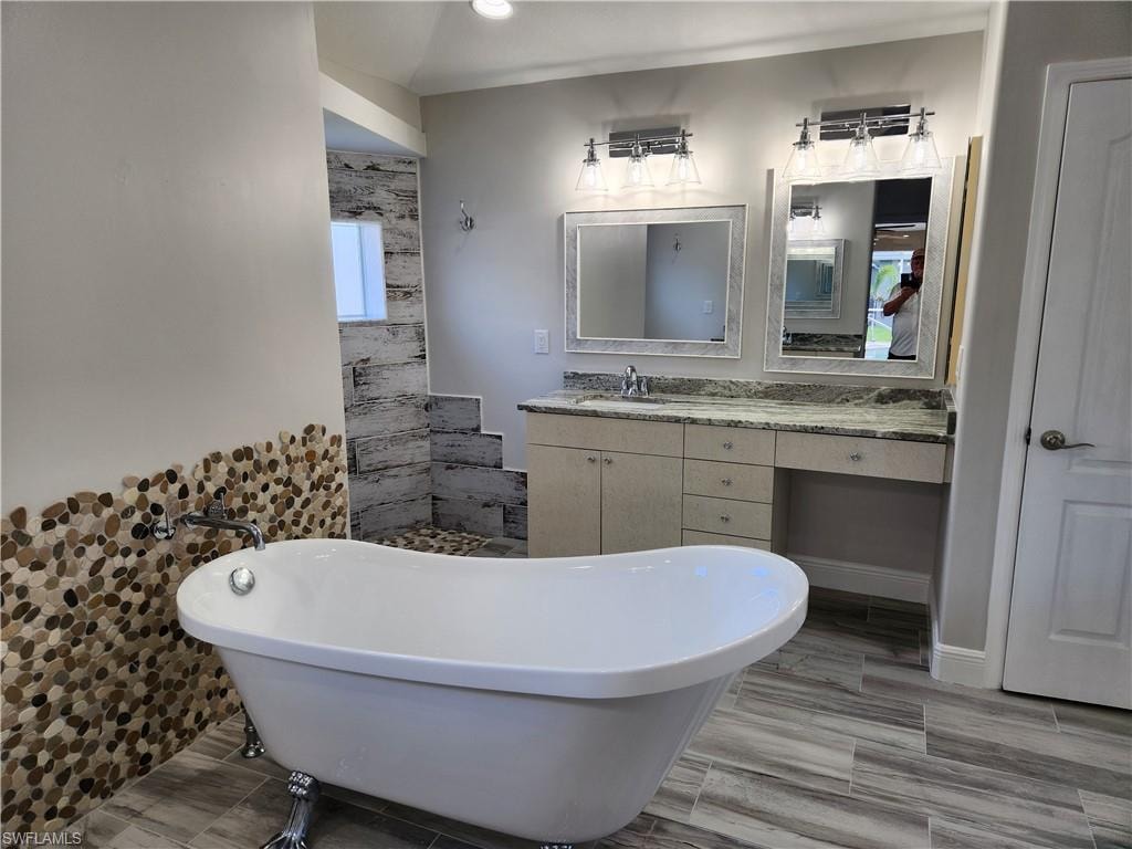 Full bath featuring a freestanding tub, vanity, tile walls, and recessed lighting