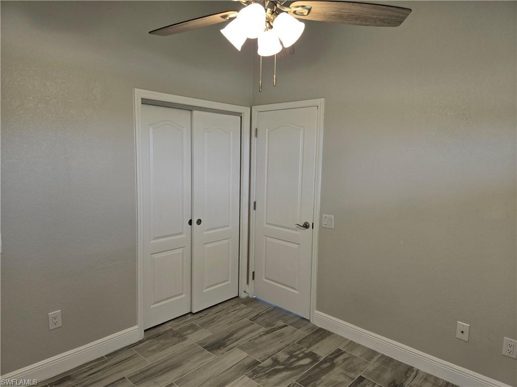 Unfurnished bedroom with a closet, ceiling fan, and wood finish floors