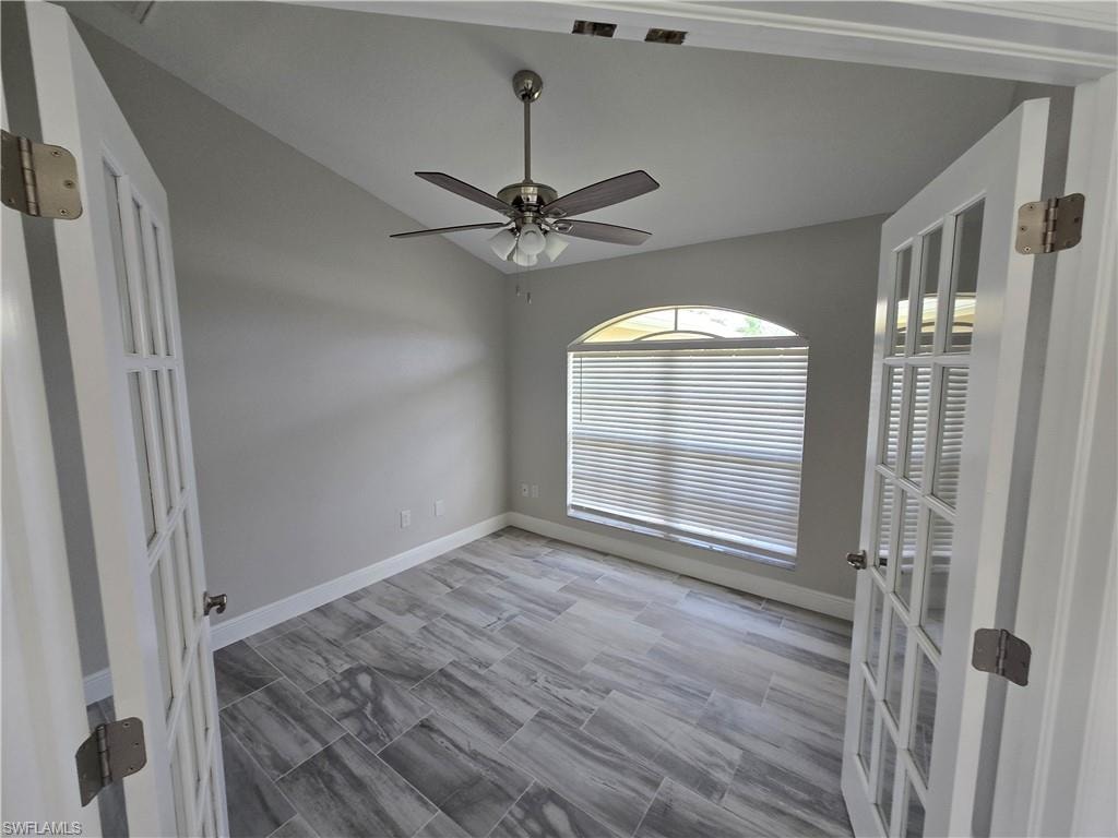 Unfurnished room with vaulted ceiling, a ceiling fan, and french doors