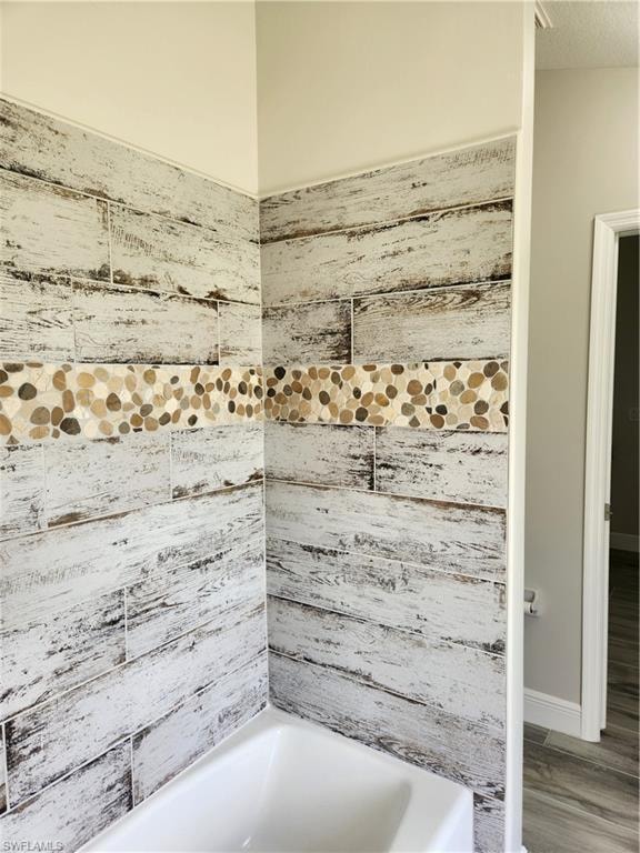 Bathroom with bathtub / shower combination and baseboards
