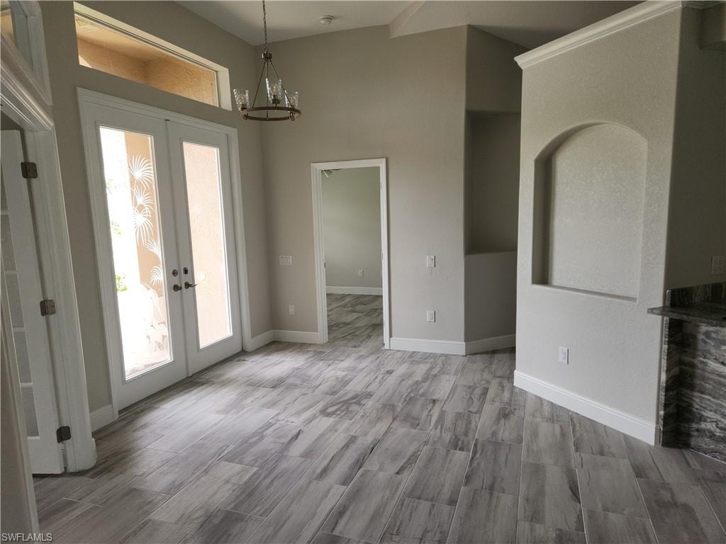 Unfurnished dining area with french doors, a chandelier, and wood finished floors