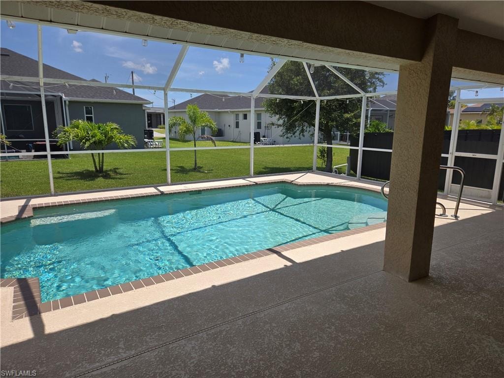Swimming pool with a patio, a lawn, and glass enclosure
