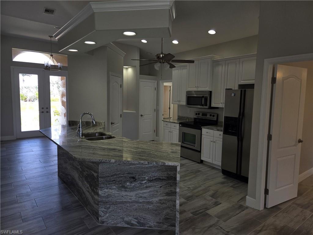 Kitchen with stainless steel appliances, white cabinetry, french doors, recessed lighting, and ceiling fan