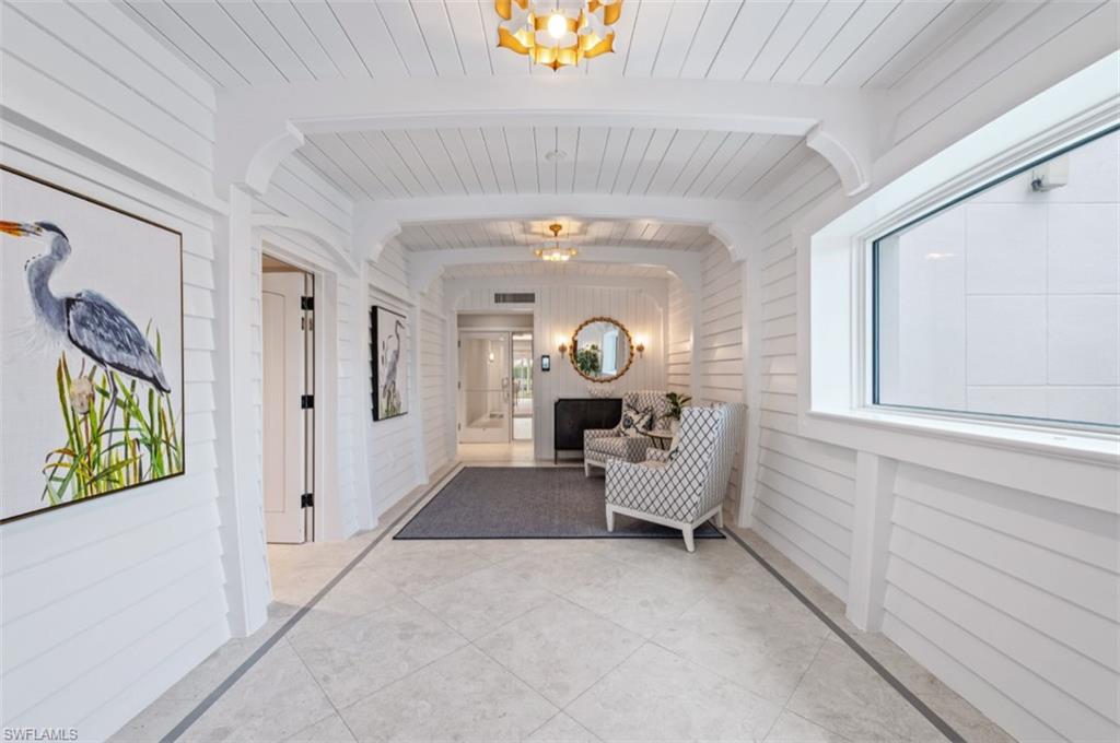 Shiplap wall and ceiling treatment, arched doorways, recessed lighting, wall sconces, and rectangular window