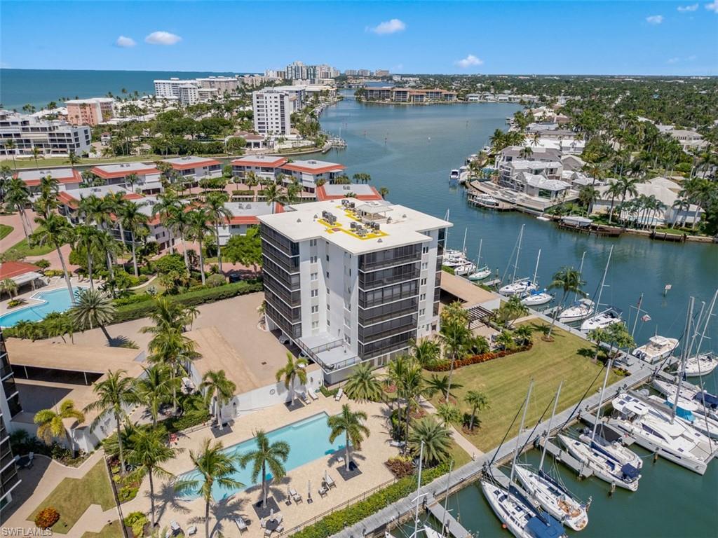 High-rise condominium building with multiple swimming pools, extensive boat docks, and lush tropical landscaping