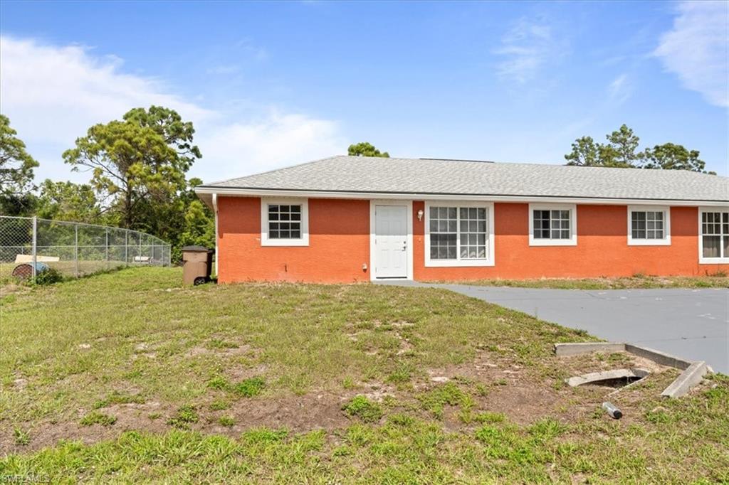 Ranch-style house featuring a front lawn, fence, and stucco siding