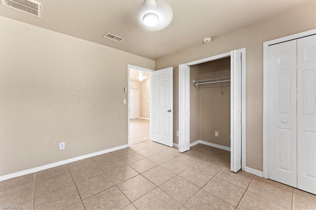 Unfurnished bedroom with multiple closets, visible vents, baseboards, and light tile patterned flooring