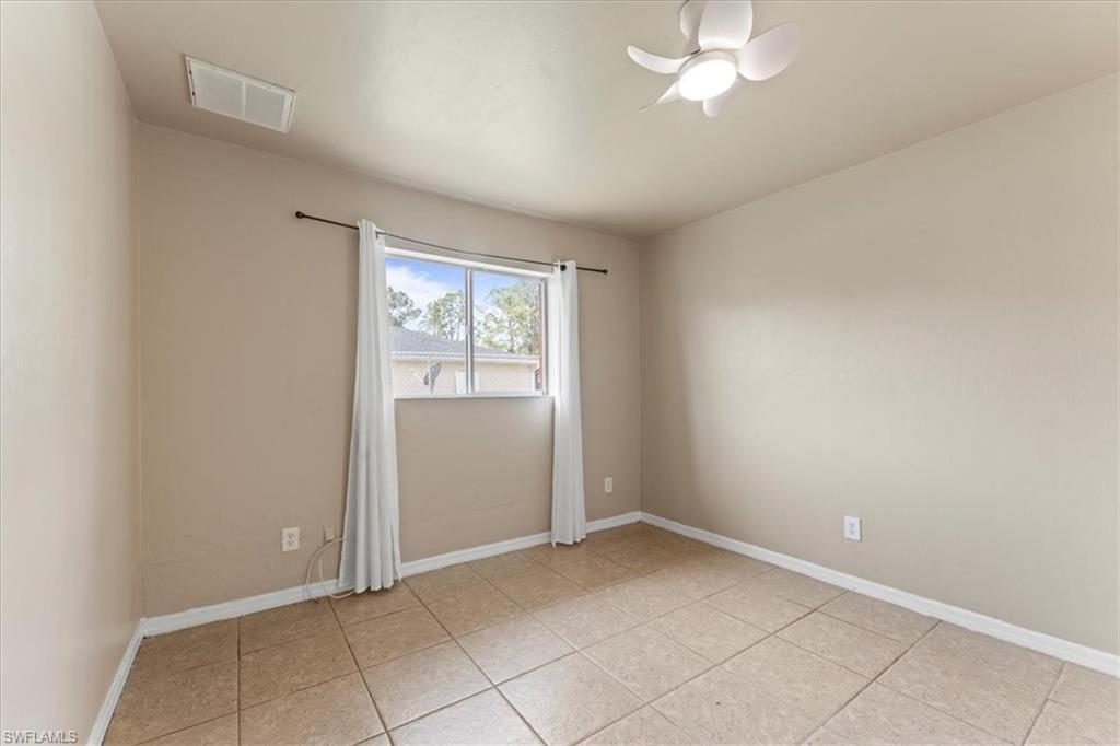 Spare room with visible vents, ceiling fan, baseboards, and light tile patterned flooring