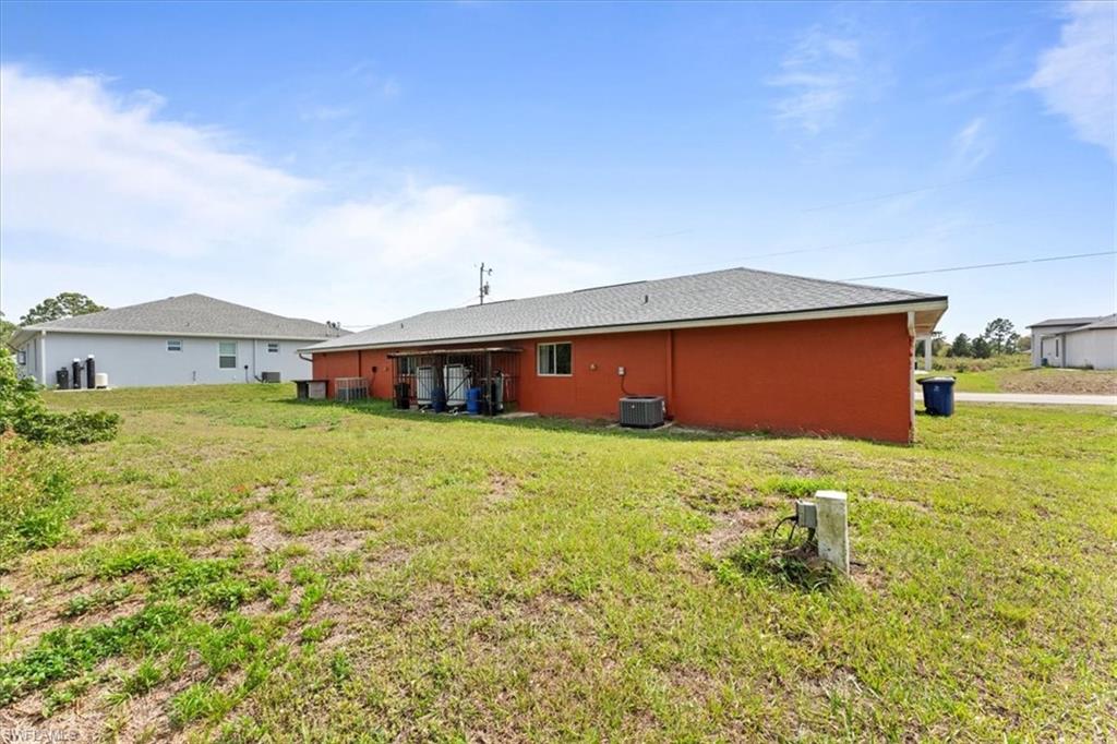 Back of property featuring a lawn and central air condition unit