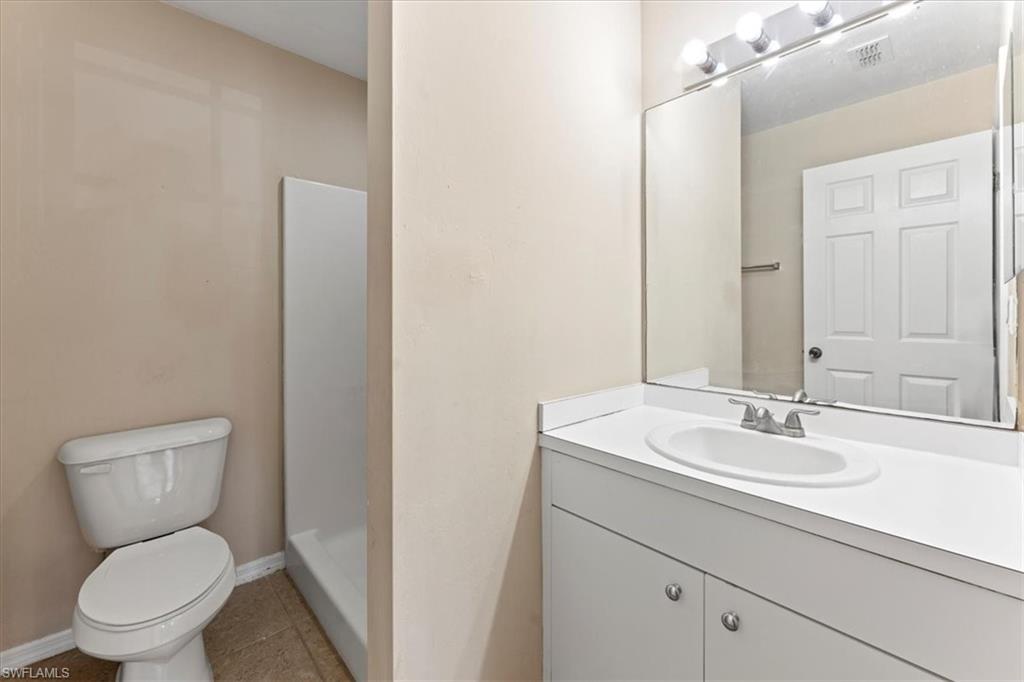 Full bath with baseboards, toilet, tile patterned flooring, vanity, and a walk in shower
