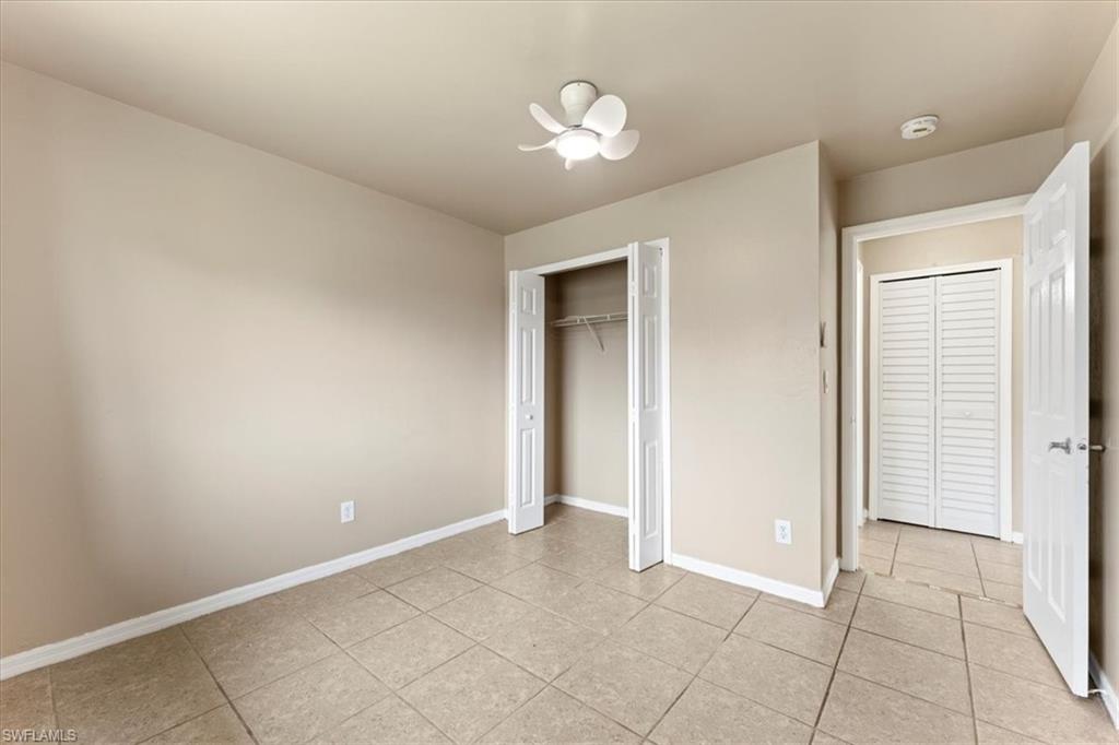 Unfurnished bedroom featuring a ceiling fan, a closet, baseboards, and light tile patterned floors