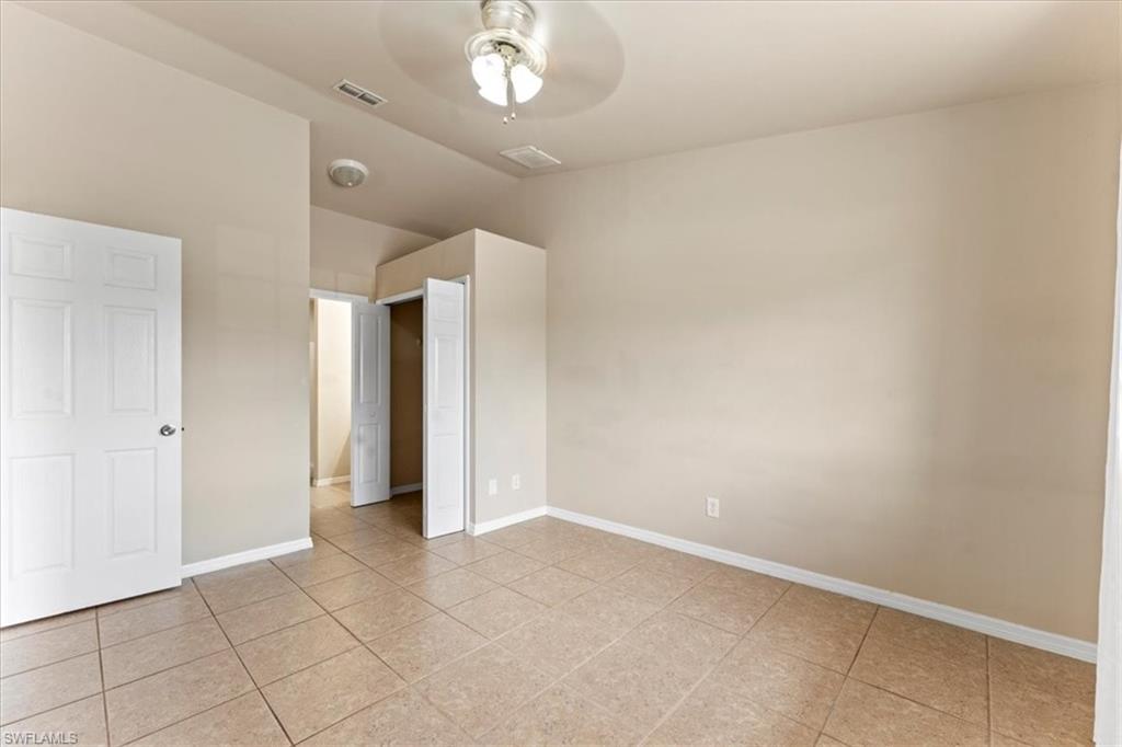 Unfurnished bedroom featuring visible vents, vaulted ceiling, baseboards, and light tile patterned floors