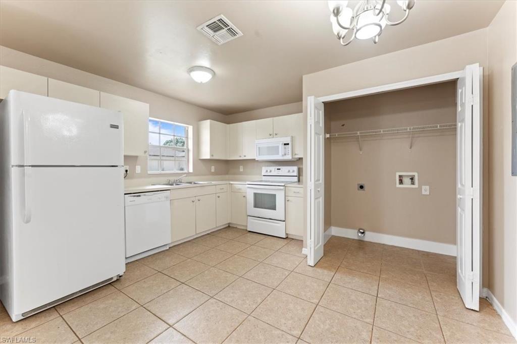 Kitchen featuring light countertops, white appliances, light tile patterned flooring, and visible vents