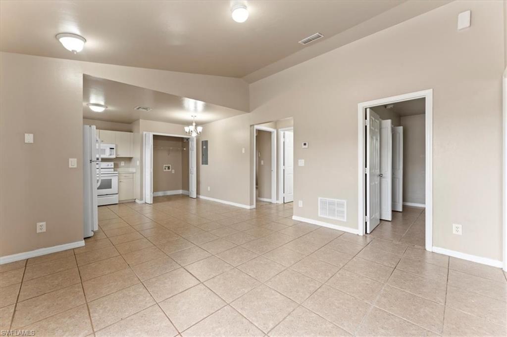 Unfurnished room featuring lofted ceiling, visible vents, a chandelier, and light tile patterned flooring