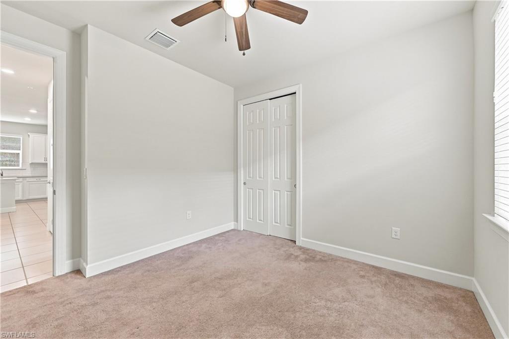 Neutral wall paint, ceiling fan, and carpeted flooring