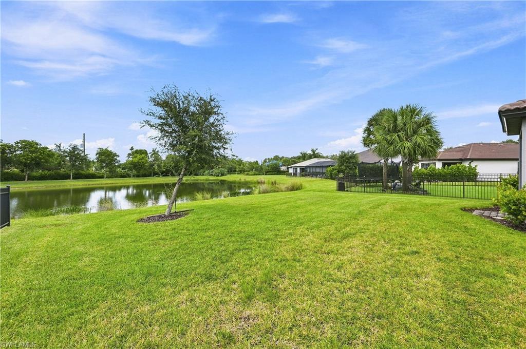 Expansive rear yard featuring a large lawn area, mature landscaping, and a water feature