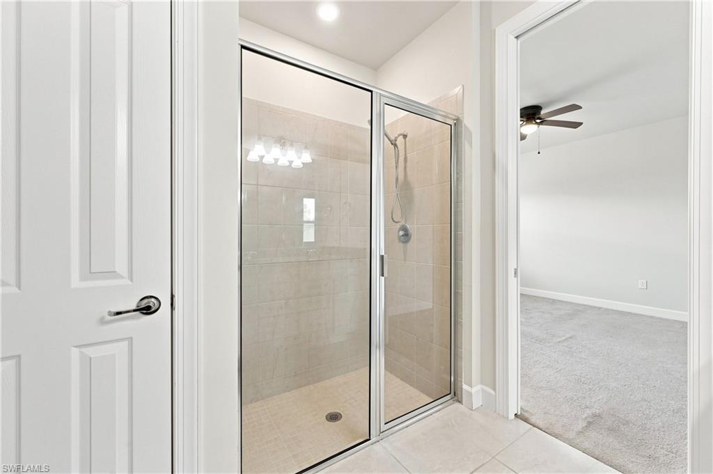 Walk-in shower with clear glass enclosure, tiled walls, and a built-in bench