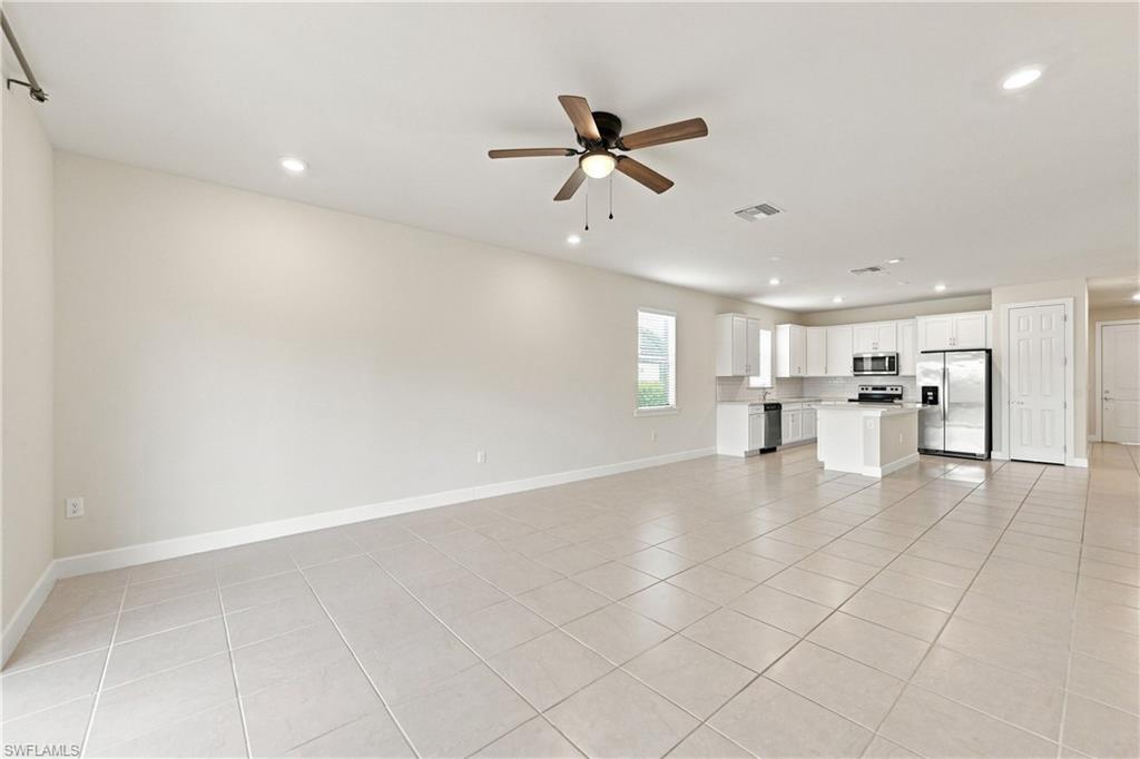 Spacious open-concept living area with tile flooring throughout, recessed lighting, and ceiling fan