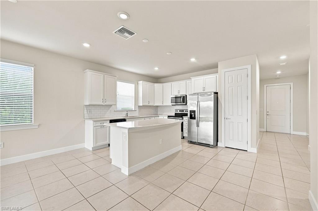 Kitchen featuring white cabinetry, a central island, stainless steel appliances, tile flooring, and recessed lighting