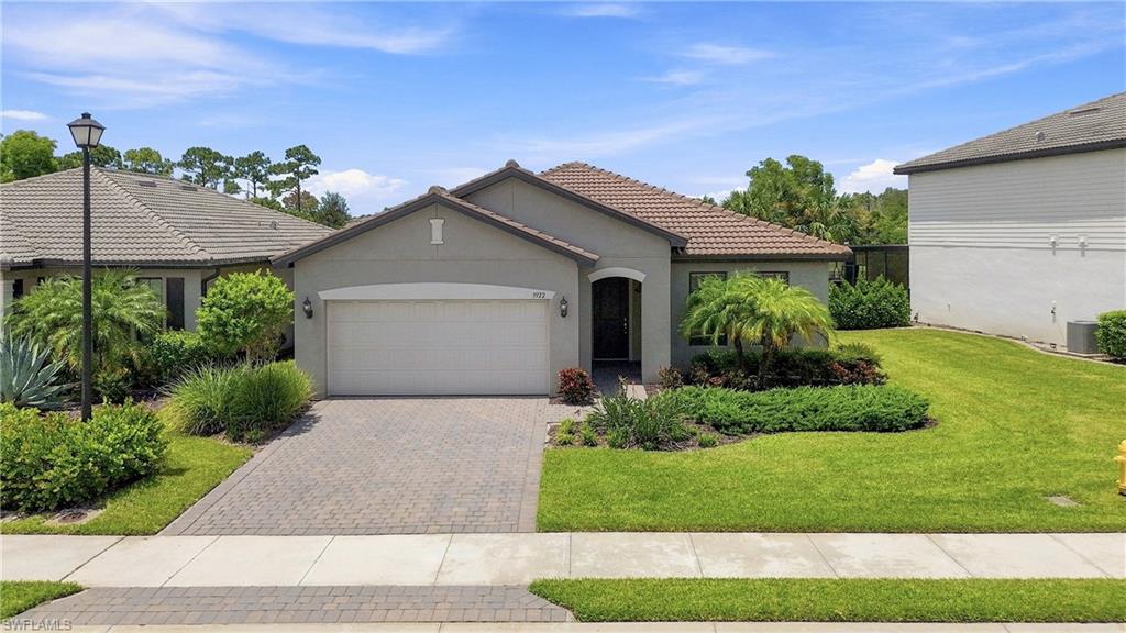 Single-story residence featuring a tile roof, paved driveway, and established landscaping