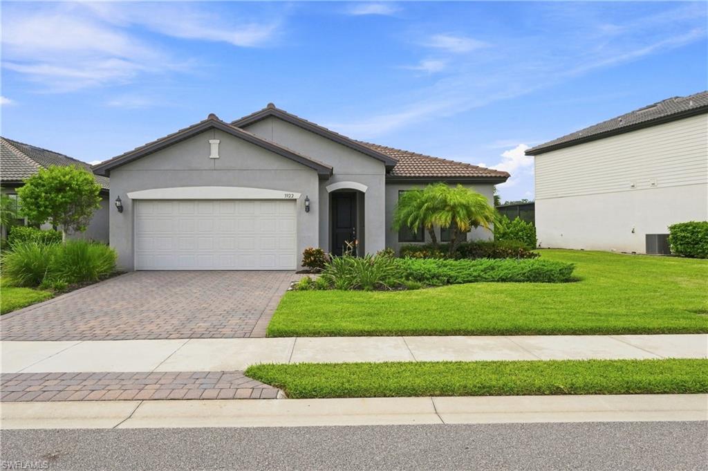 Stucco exterior with a tile roof, paver driveway, and a covered entryway