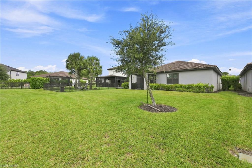 Expansive manicured lawn with mature landscaping and established trees, complemented by multiple single-story residences with neutral exterior finishes and pitched rooflines positioned throughout the property grounds