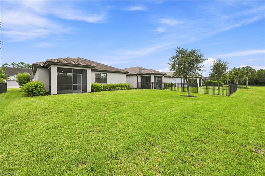 Expansive manicured lawn with mature landscaping and black perimeter fencing