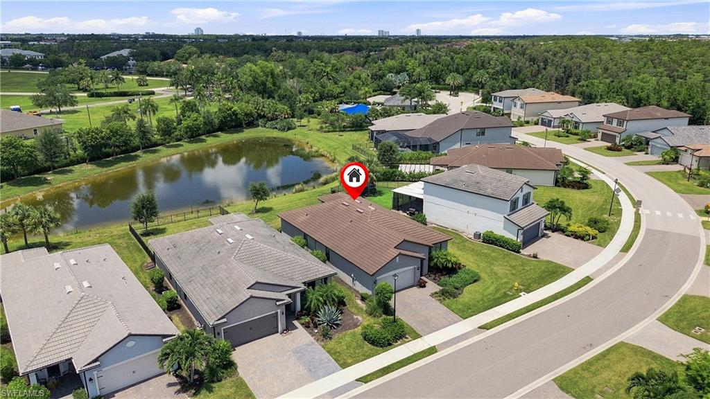 Aerial view of this lakefront residential community showcasing a contemporary home with a bronze metal roof, attached garage, and manicured landscaping