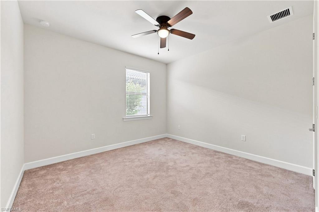 Carpeted room featuring a ceiling fan with integrated lighting, a window with blinds, and white trim